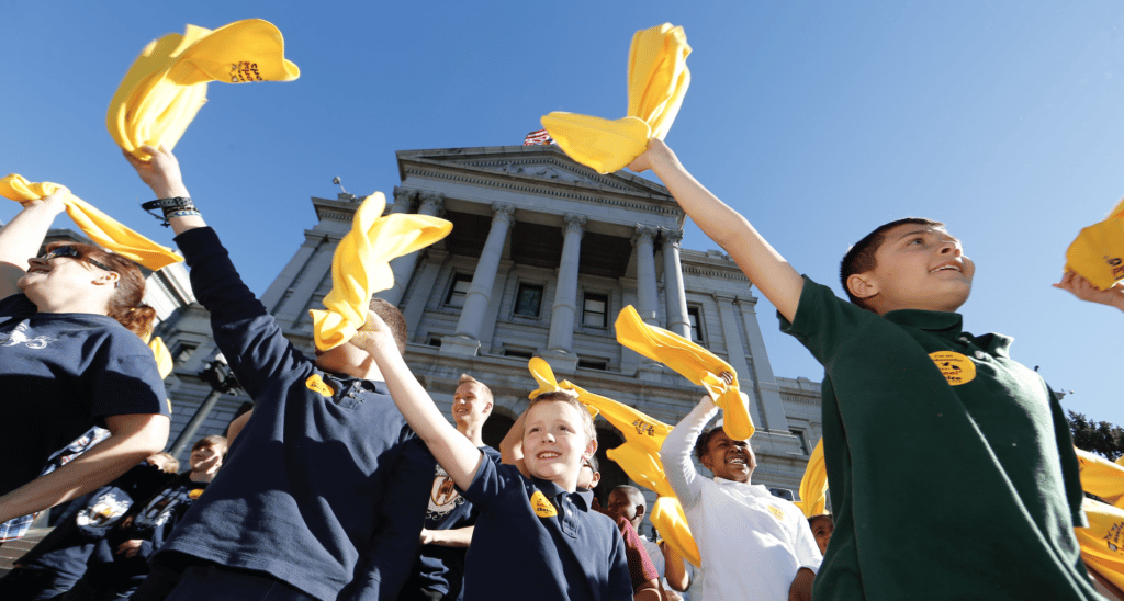 students on state capitol steps waive yellow scarves